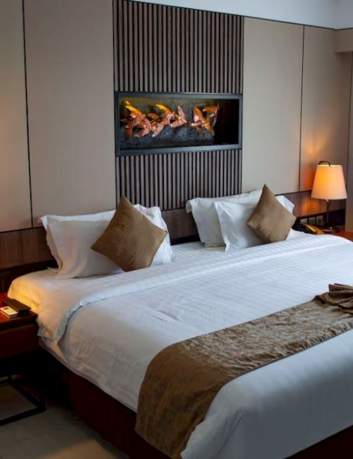 This image shows a well-decorated hotel room with a large bed, lamps, pillows, bedside tables, and a window with curtains on the right.