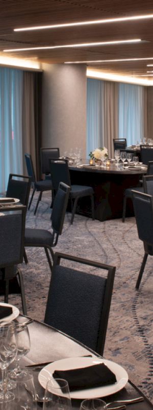 This image shows an elegant banquet hall with round tables set for a formal event, featuring modern decor, soft lighting, and neatly arranged table settings.