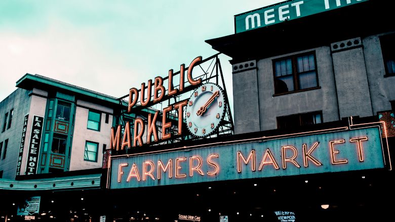 A public market sign with a clock and a 